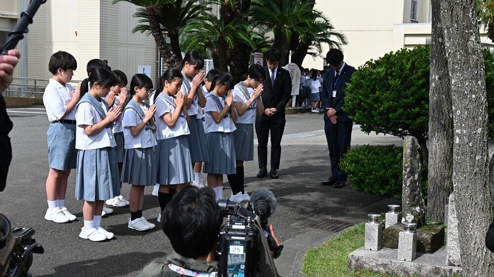 慰霊碑に向かって祈りを捧げる児童
