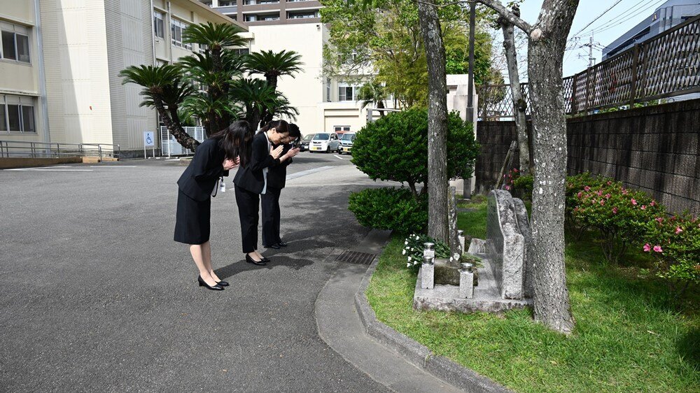 慰霊碑に向かって祈りを捧げる学校関係者